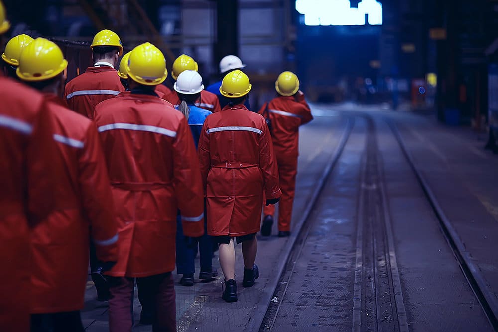 Industrial Workers Walk Along a Train Track