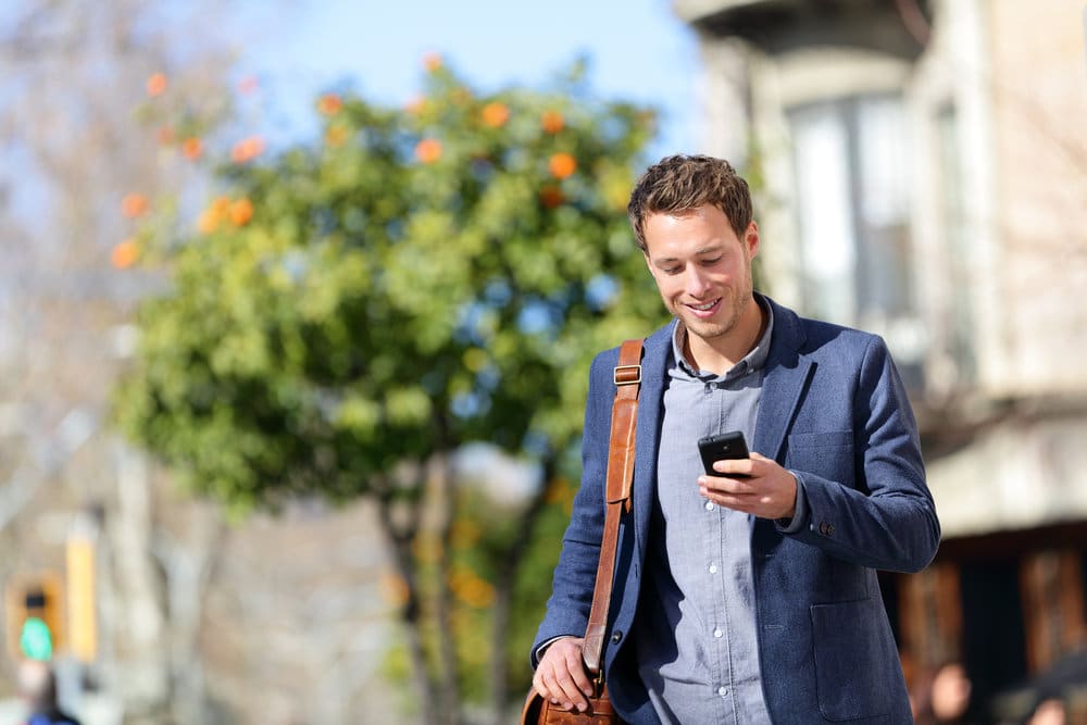 Man Walking Outside Smiling At His Phone