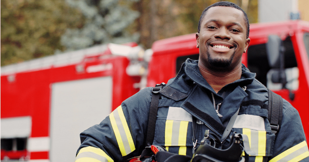 Male Fireman Smiling in Front of a Firetruck