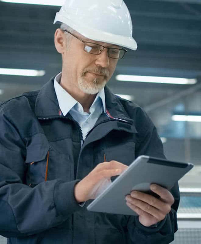 Male Engineer Wearing a Hardhead on a Tablet in a Factory
