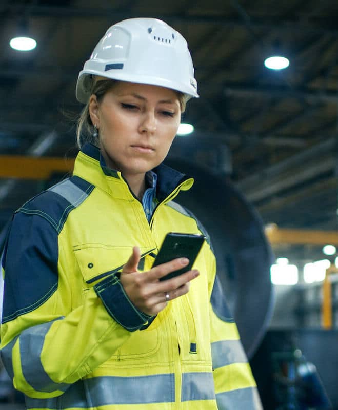 Female Engineer Wearing a Hard Hat On Phone In Factory