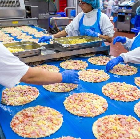 Factory Workers Following Food Safety Protocols While Making Hawaiian Pizza