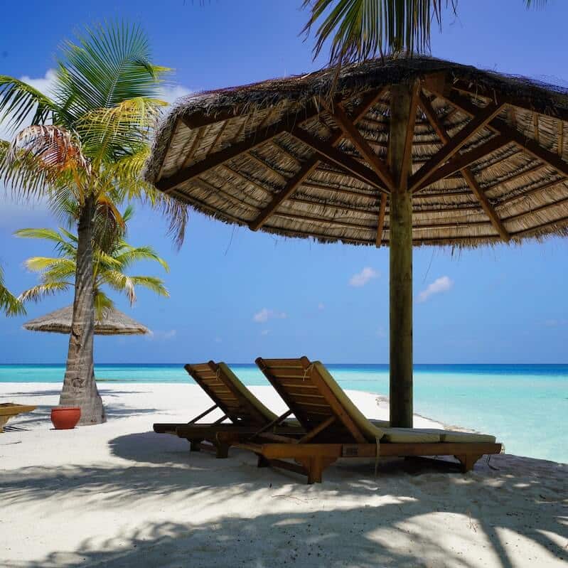 Beach Vacation With Two Chairs and a Shade Outlooking the Clear Blue Ocean