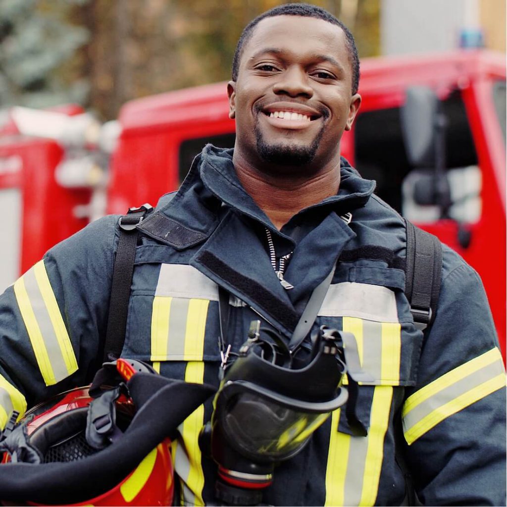 Male Fireman Smiling in Front of a Firetruck