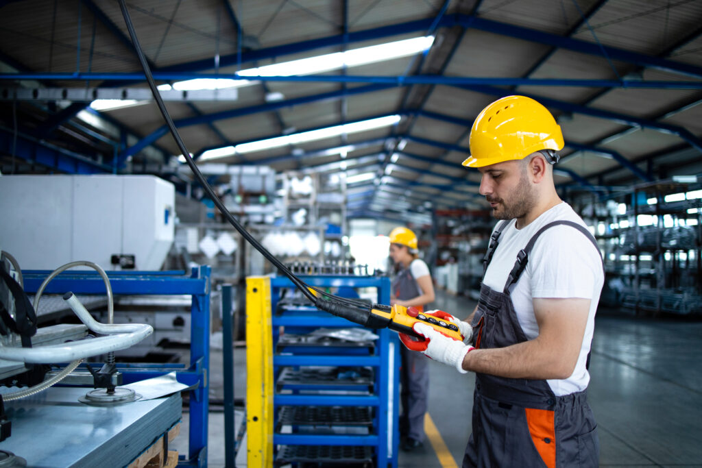 Factory,worker,wearing,uniform,and,hardhat,operating,industrial,machine,with