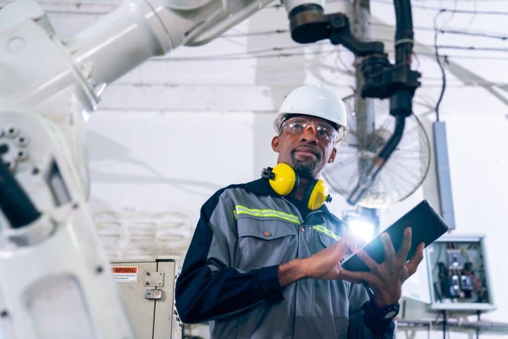 African,american,factory,worker,working,with,adept,robotic,arm,in