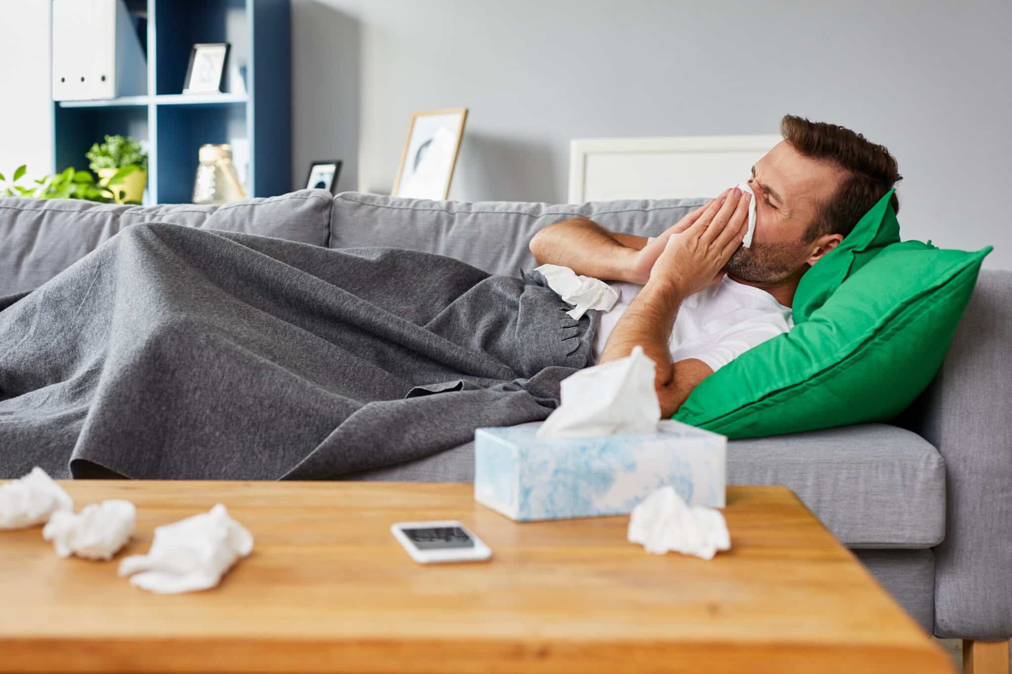 Sick,man,lying,on,sofa,at,home,and,blowing,nose