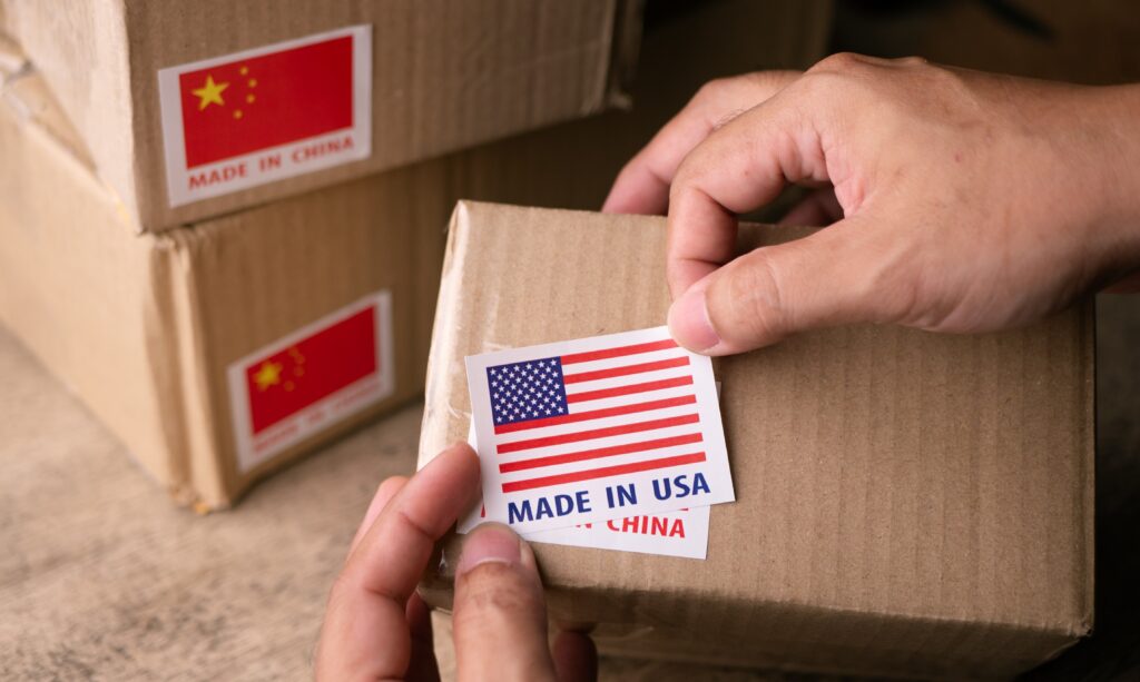 Reshoring Manufacturing From China To Usa; Cardboard boxes with a hand applying stickers