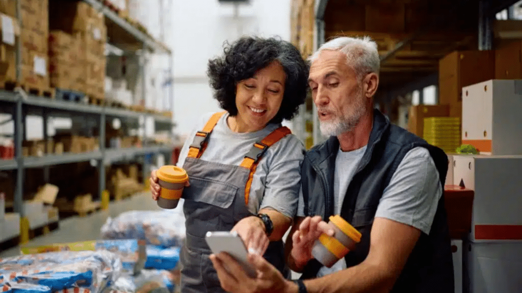 Happy,warehouse,worker,and,her,colleague,using,smart,phone,while, Communication In The Workplace