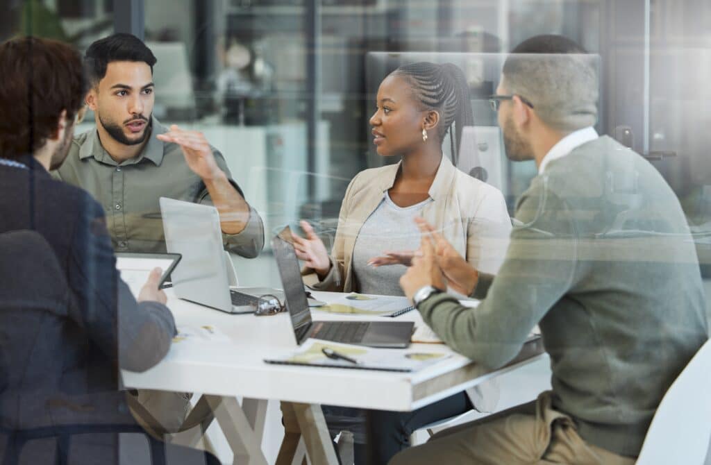 Meeting,,collaboration,and,business,people,in,discussion,in,the,office, 4 Business People at Table Discussing Workforce Planning Analytics