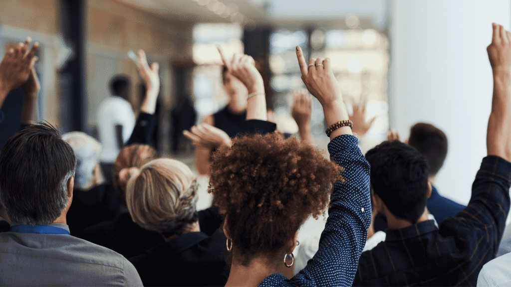 Room full of employees raising their hands for the employee attendance policy
