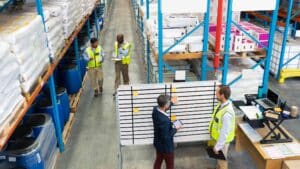 A stock photo of a supervisor viewing a complex, multi-shift industrial schedule with his team in a plant setting.