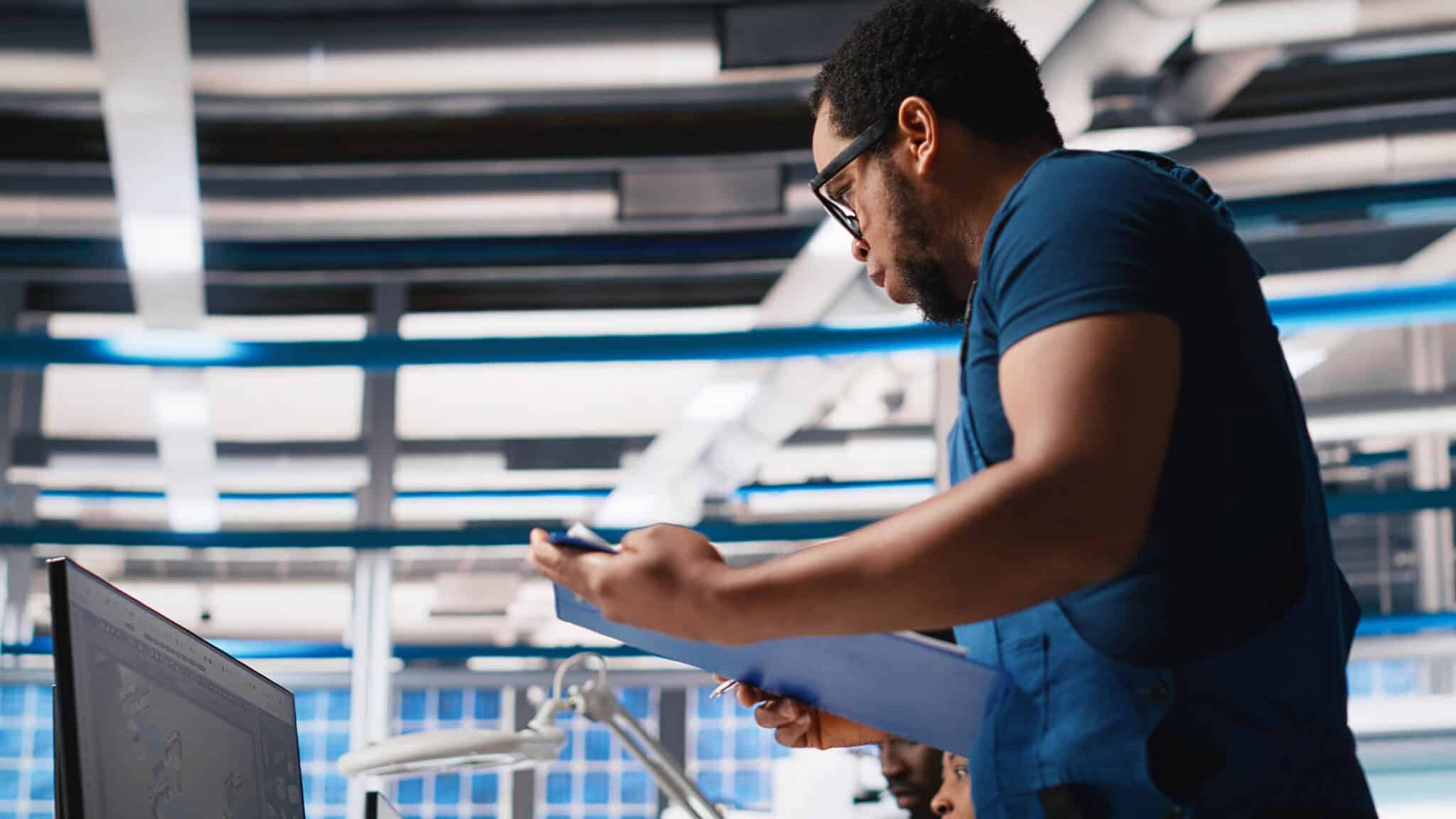 A stock photo of a man wearing glasses looking at a new scheduling interface on a monitor.