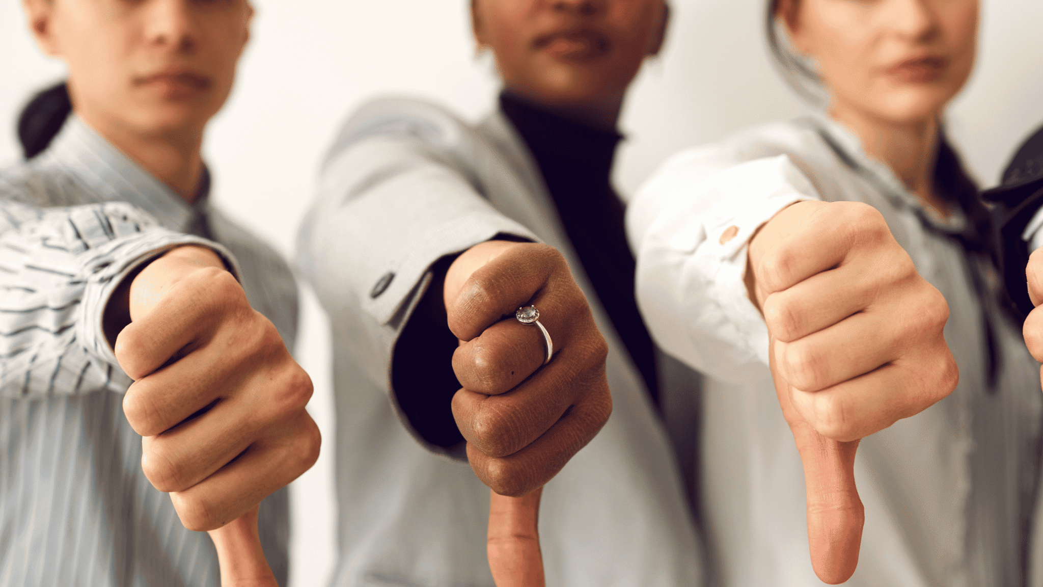 Three women in business attire giving a thumbs down signaling Signs of a Toxic Work Environment